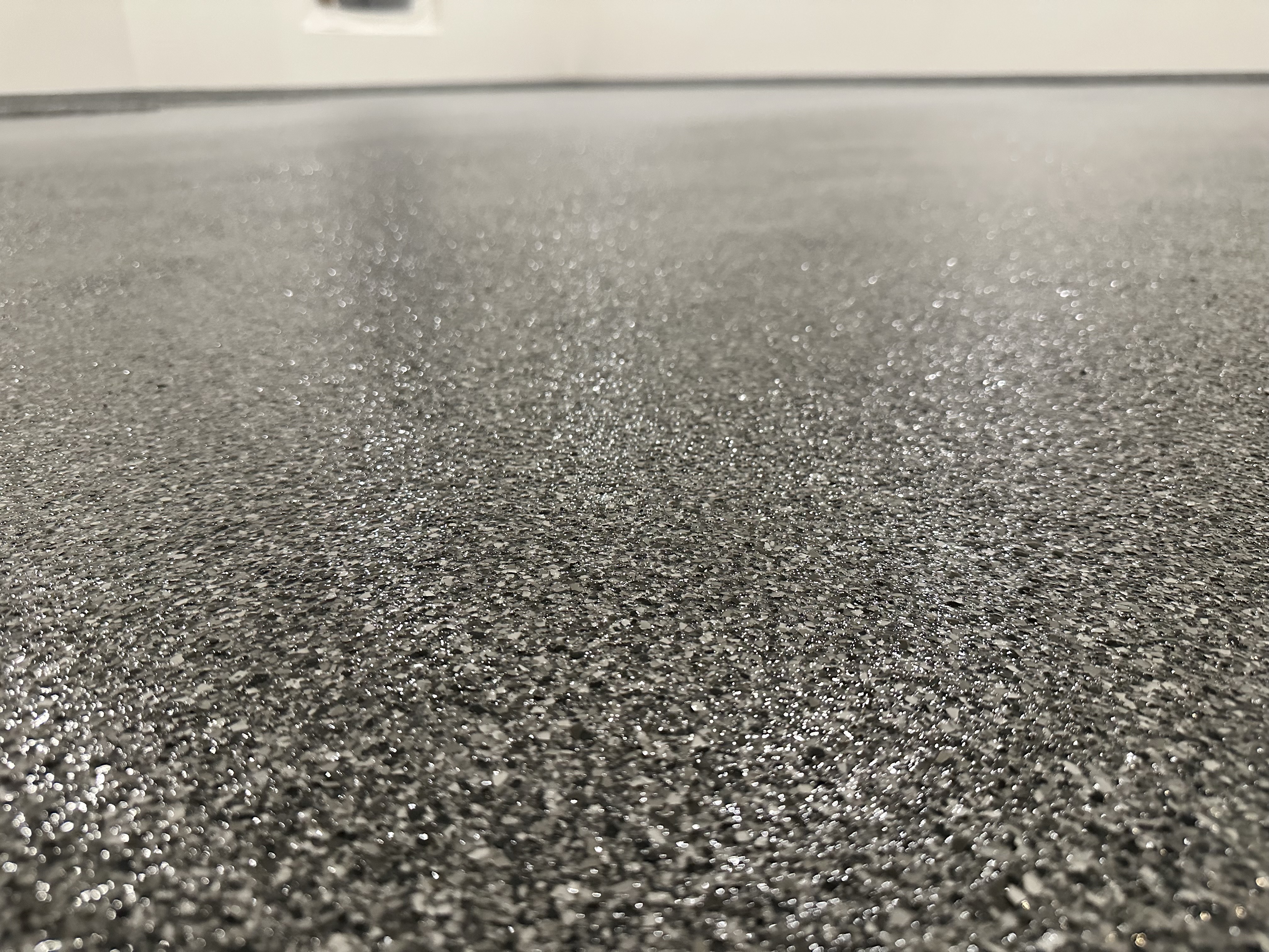 Charcoal flake floor with metallic accent — close-up