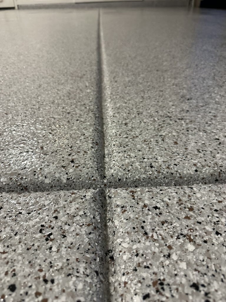Closeup of a flake floor with a saw-cut control joint, showing crack repair detail.